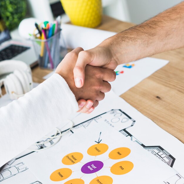 close-up-two-businessmen-shaking-hands-desk_23-2147839892