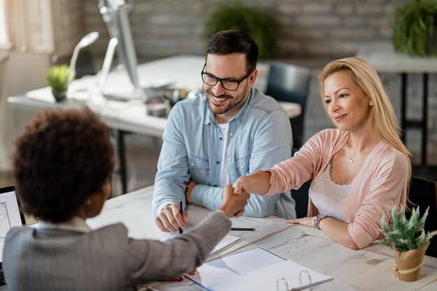 mid-adult-couple-reaching-agreement-with-real-estate-agent-office-women-are-handshaking_637285-1732